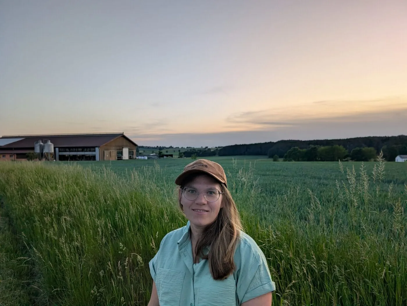 Theresa Bäuml in einem Feld vor einem landwirtschaftlichen Betrieb im Abendlicht